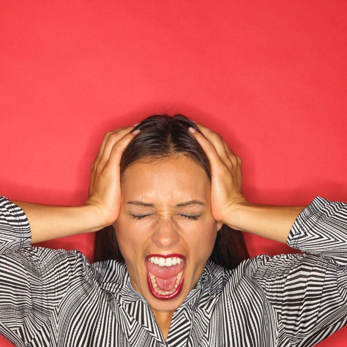 Woman holding her head screaming.
