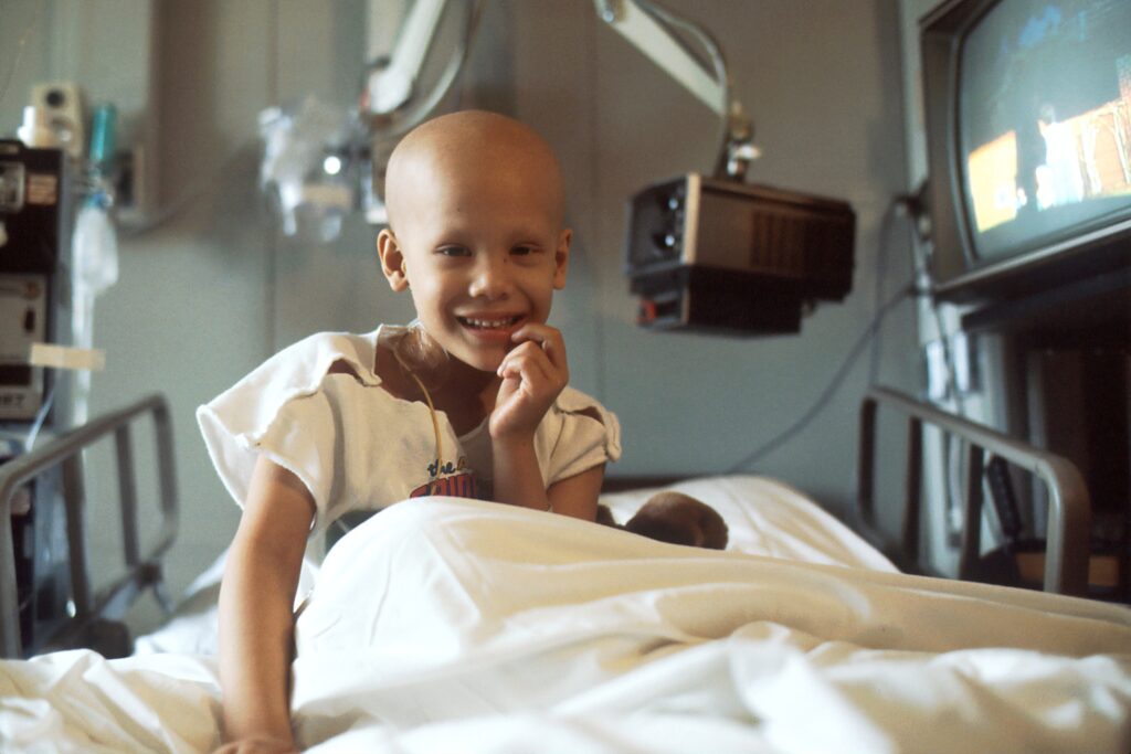 child with cancer sitting in a hospital bed