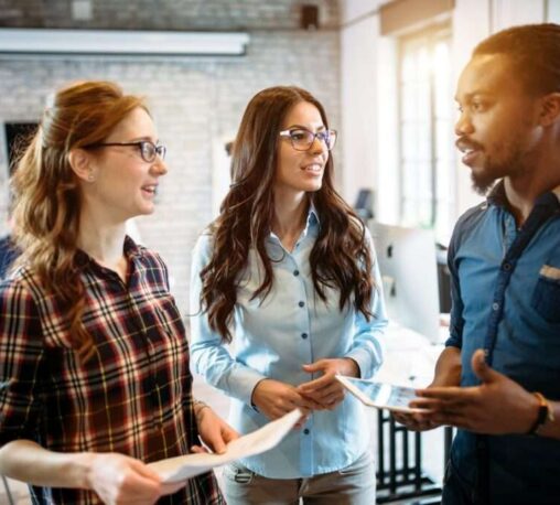 Three professionals collaborating in a modern office environment, representing teamwork and communication at Towner Communications in Kansas City.