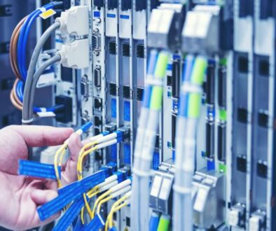 A technician installing structured cabling in a data center, connecting fiber optic and Ethernet cables for a high-performance business network.