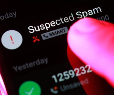 Close-up of a smartphone screen displaying a suspected spam call alert with a finger hovering to block the number
